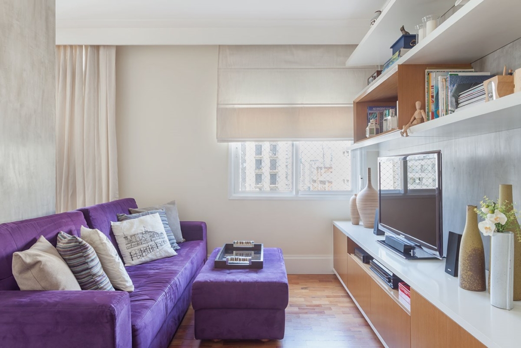 sala com sofa roxo e estantes com tv e livros