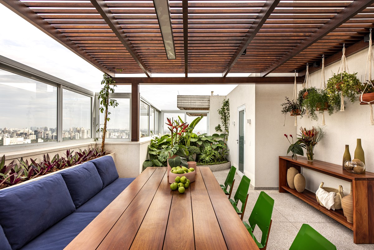 cobertura com mesa de madeira com maças verdes ao centro e decoração de plantas