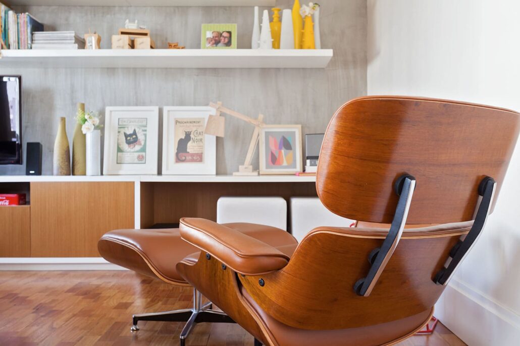 poltrona em madeira, estantes com tv, livros e quadros