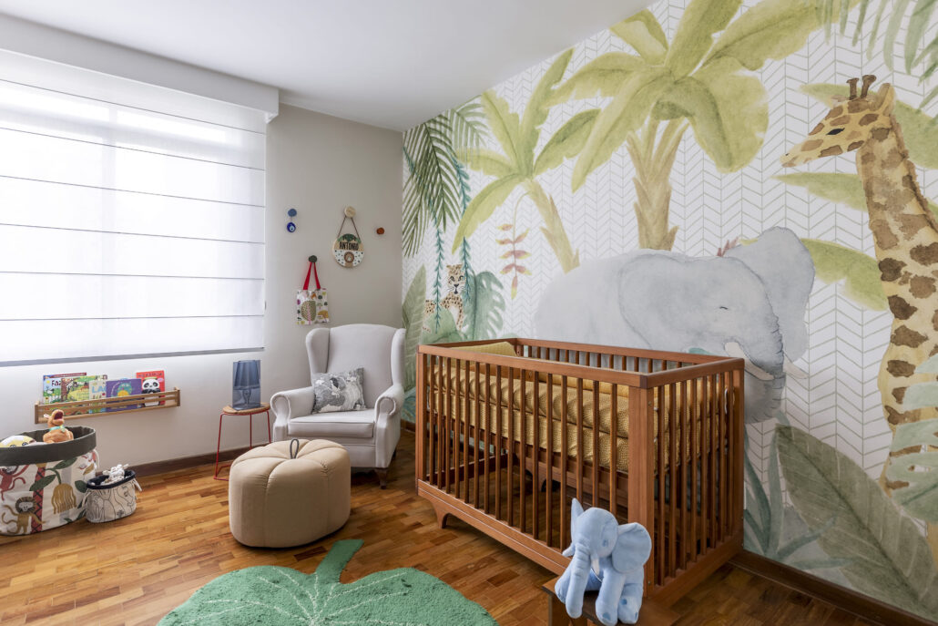 quarto infantil com pinturas de safari na parede, no canto uma poltrona cinza um berço em madeira