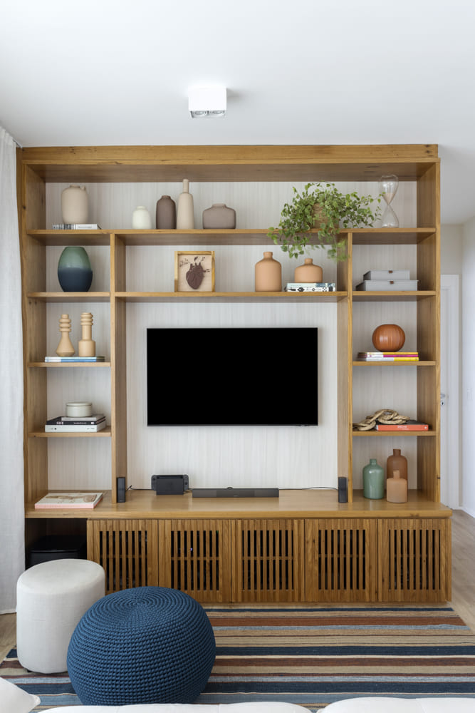 estante com televisao ao centro e vasos de decoração