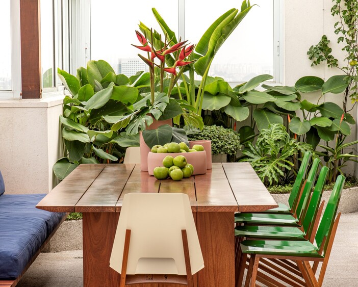 mesa de madeira com maças verdes ao centro e decoração de plantas