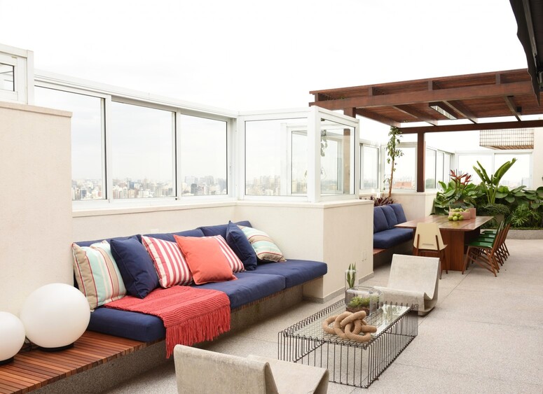 cobertura com sofá azul e vermelho com almofadas, mesa de centro e cadeiras